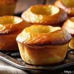 요크셔 푸딩 만드는 법 - A close-up of perfectly golden Yorkshire puddings fresh from a high-temperature oven, showing a cris...